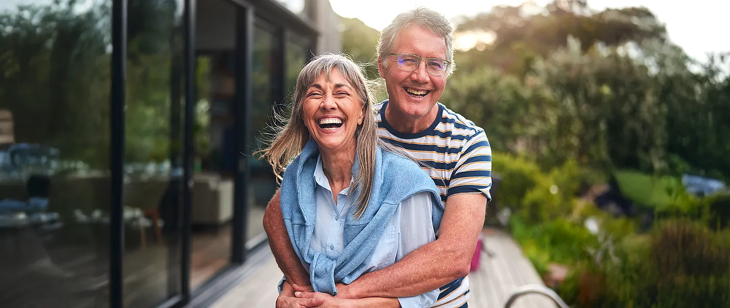 Reifes Paar, das Arm in Arm steht und im Sommer draußen lacht.