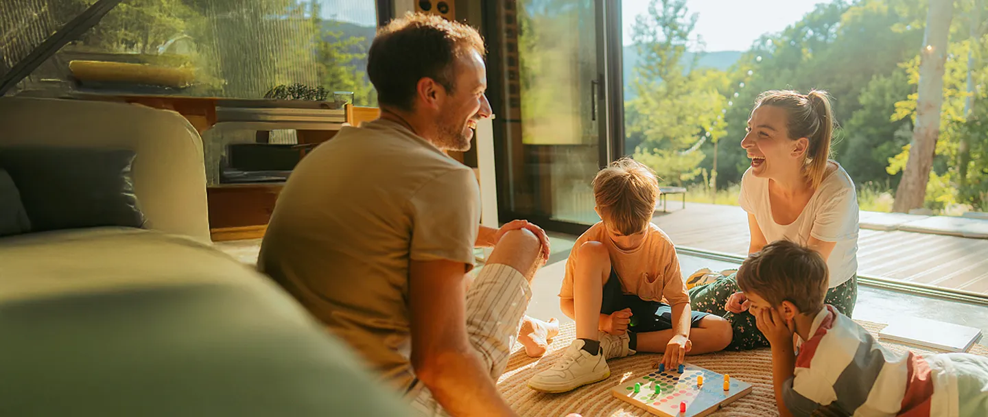 Eine Familie spielt zuhause zusammen ein Gesellschaftsspiel.