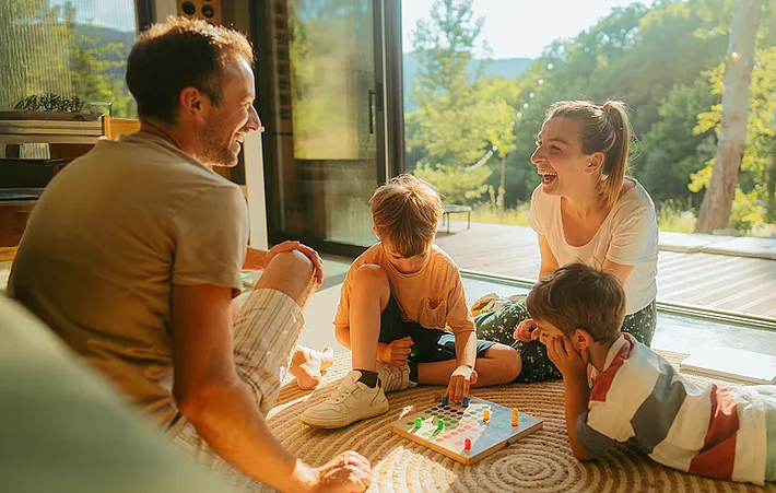 Eine Familie spielt zuhause zusammen ein Gesellschaftsspiel.